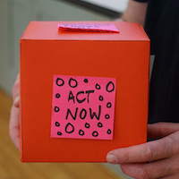 Foto: Box mit Haftnotiz "Act now" wird gehalten